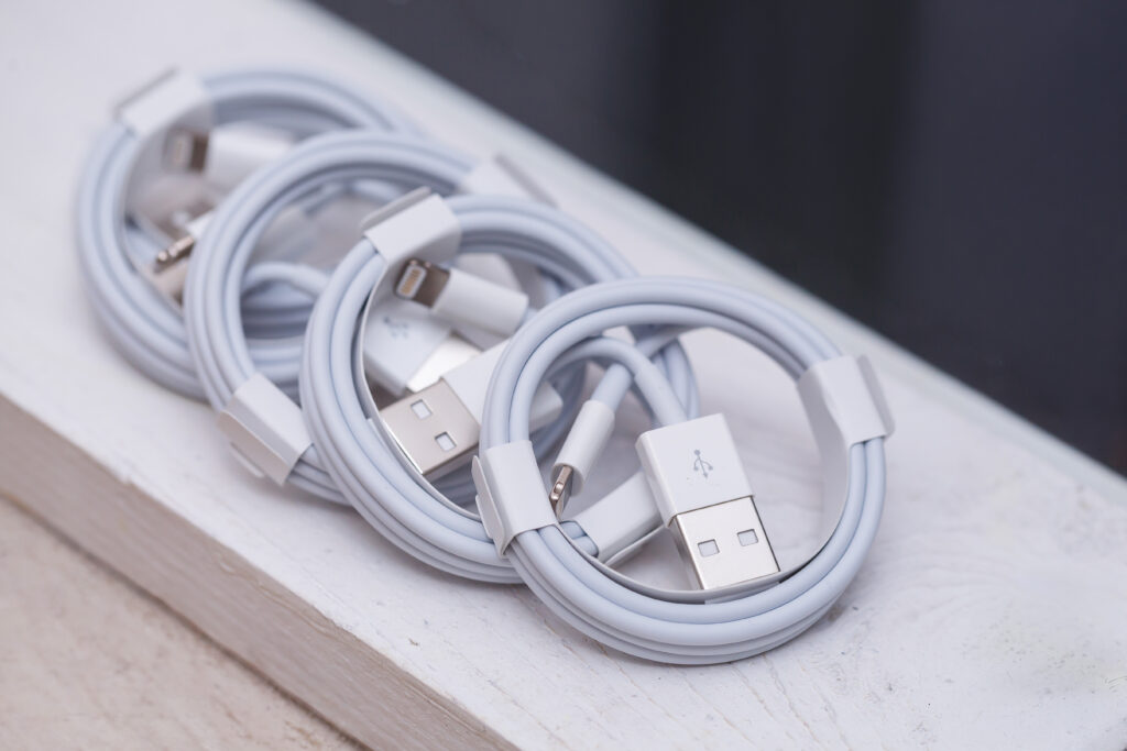 Quatre câbles Lightning vers USB-A blancs enroulés côte à côte sur une étagère