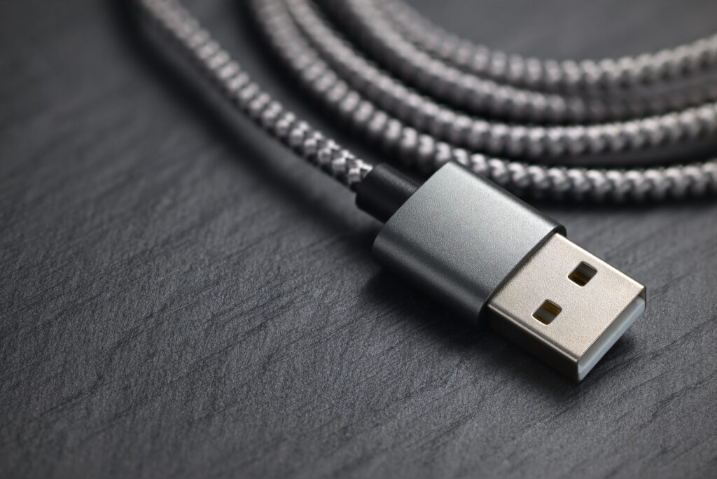 Câble de charge en nylon tressé gris à connecteur USB-A métallique, posé sur une ardoise noire