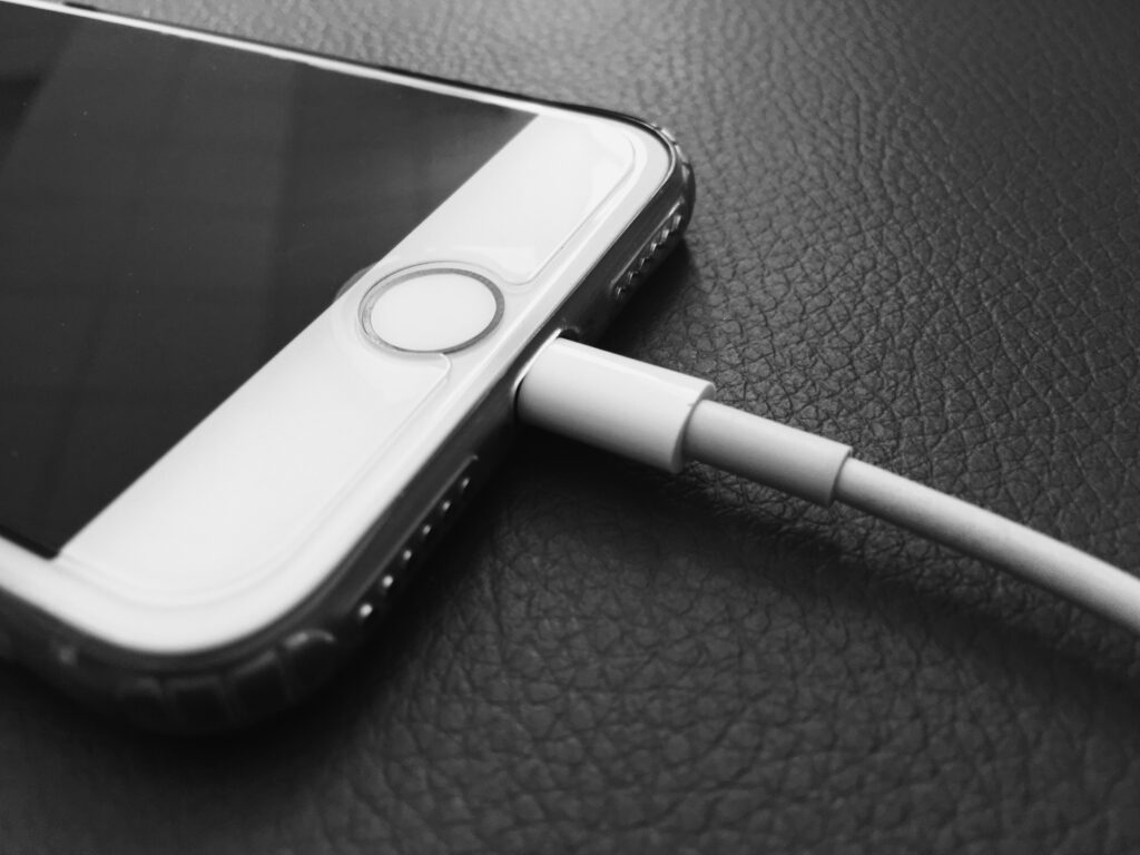 iPhone branché sur un câble de charge Lightning blanc, photo en noir et blanc