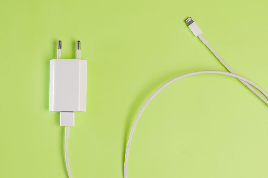 Bloc chargeur secteur blanc relié à un câble à connecteur Lightning, sur fond vert
