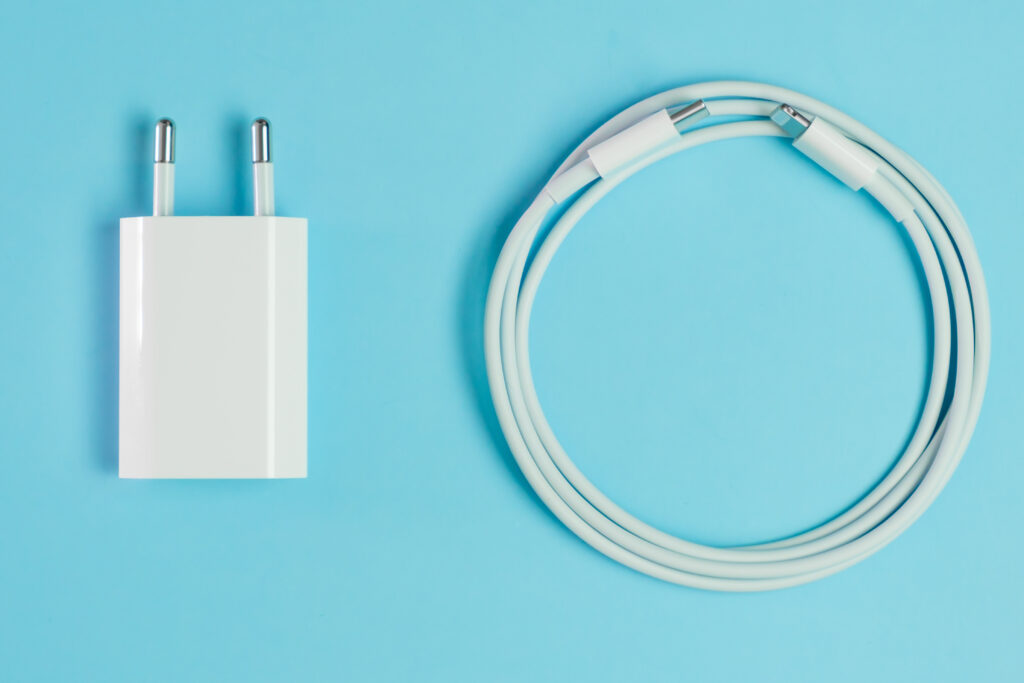 Bloc chargeur secteur USB blanc et câble de charge pour iPhone enroulé, sur fond bleu